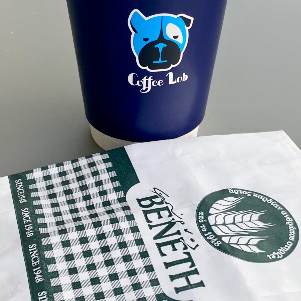 Στην φωτογραφία είναι ένα κύπελο καφέ Coffee Lab και μια σακούλα χάρτινη ΒΕΝΕΤΗΣ